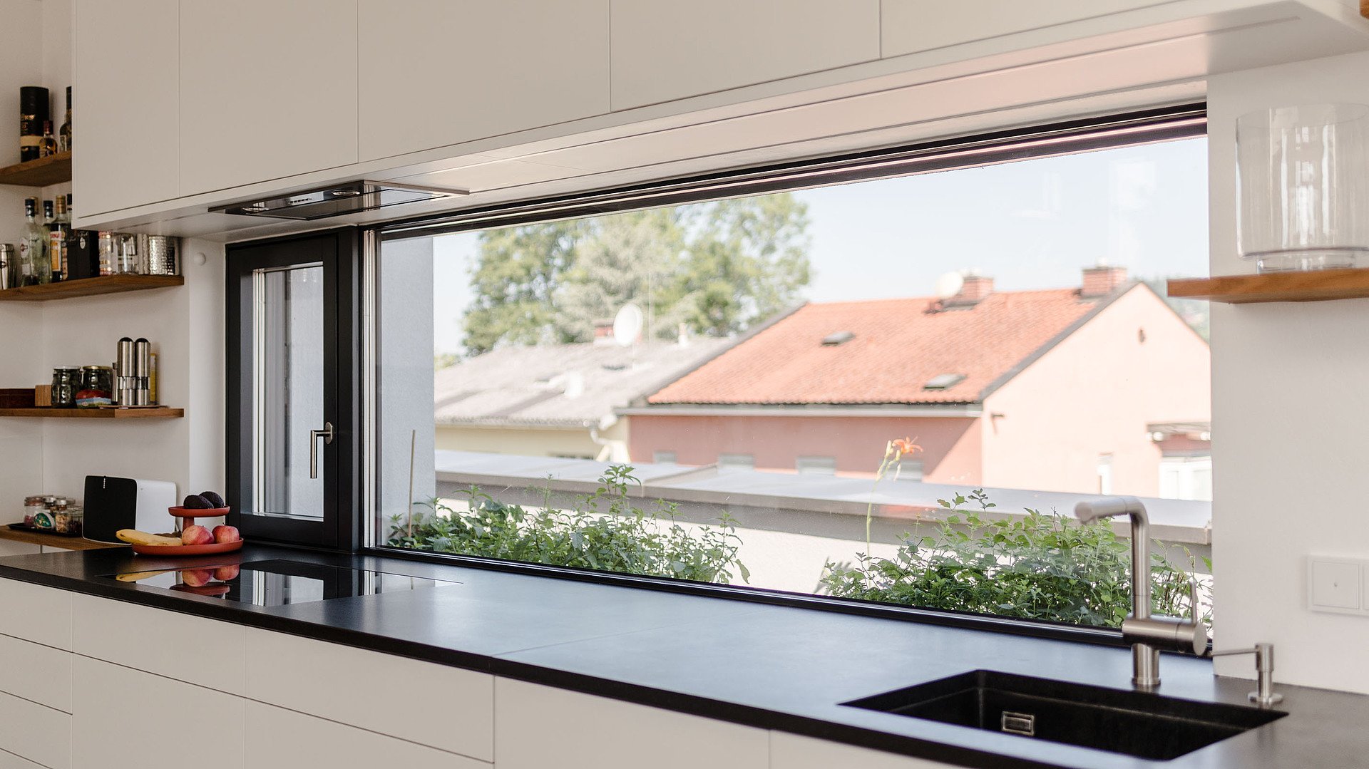 Moderne Küchenlösung mit großem Aluminium-Fenster und freiem Ausblick – hochwertige Fenster in Esslingen für lichtdurchflutete Wohnräume und modernen Sonnenschutz.