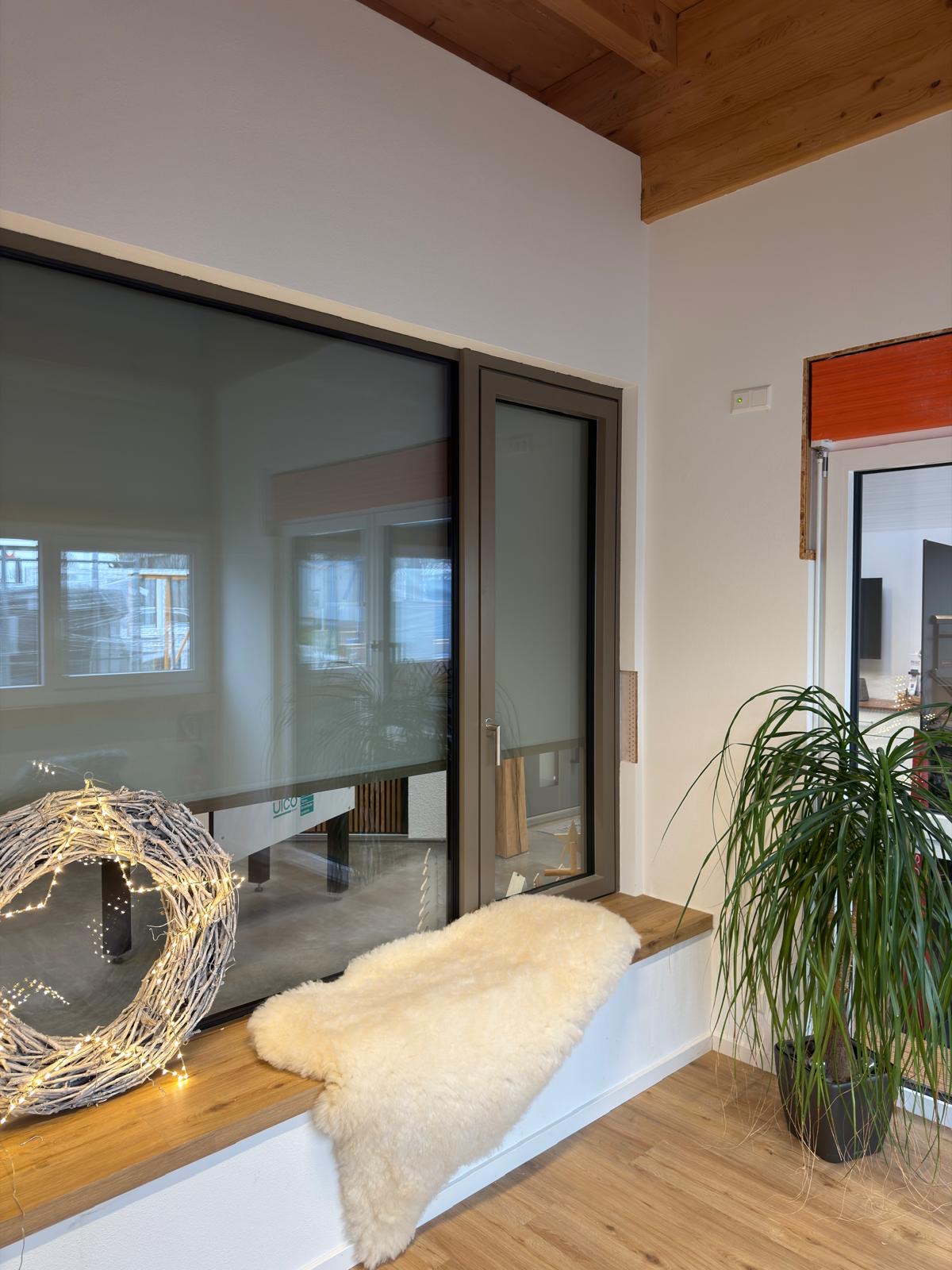 Moderne Fensterlösung mit großflächiger Verglasung und integriertem Sonnenschutz – stilvolle Kombination aus Design, Tageslicht und Wohnkomfort in natürlicher Holzoptik.